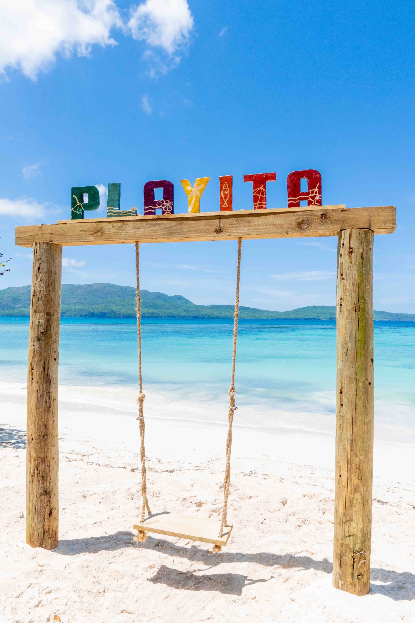 Cartel y columpio frente al mar en Playa La Playita, Las Galeras